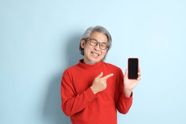 Mavi arka planda duran kıdemli Asyalı adam..