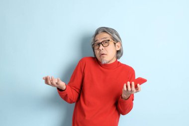 Mavi arka planda duran kıdemli Asyalı adam..