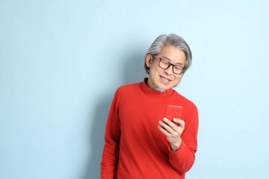 Mavi arka planda duran kıdemli Asyalı adam..