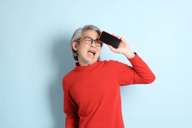 Mavi arka planda duran kıdemli Asyalı adam..