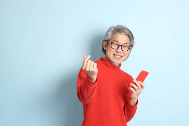 Mavi arka planda duran kıdemli Asyalı adam..