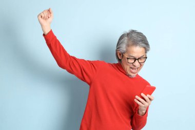 Mavi arka planda duran kıdemli Asyalı adam..