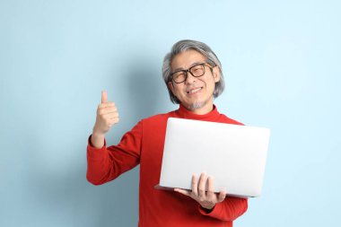 Mavi arka planda duran kıdemli Asyalı adam..