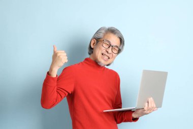 Mavi arka planda duran kıdemli Asyalı adam..