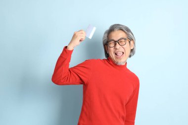 Mavi arka planda duran kıdemli Asyalı adam..