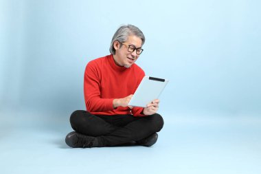 Mavi arka planda duran kıdemli Asyalı adam..