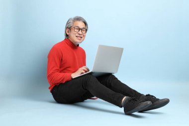 Mavi arka planda duran kıdemli Asyalı adam..