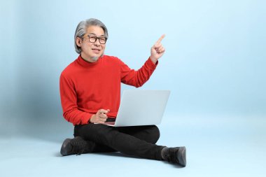 Mavi arka planda duran kıdemli Asyalı adam..