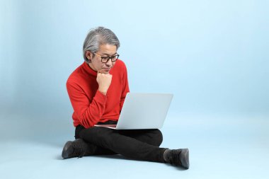 Mavi arka planda duran kıdemli Asyalı adam..