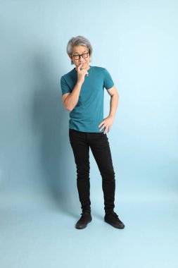 Mavi arka plandaki kıdemli Asyalı adam..