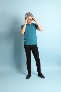 Mavi arka plandaki kıdemli Asyalı adam..