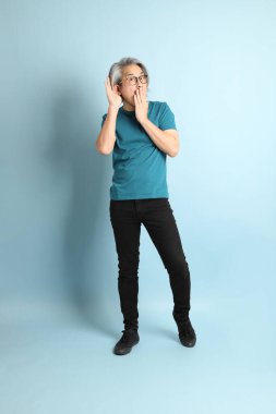 Mavi arka plandaki kıdemli Asyalı adam..