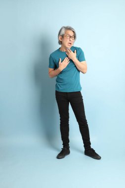 Mavi arka plandaki kıdemli Asyalı adam..