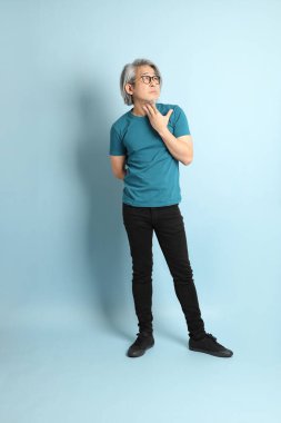 Mavi arka plandaki kıdemli Asyalı adam..