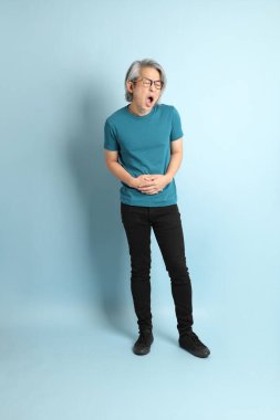 Mavi arka plandaki kıdemli Asyalı adam..