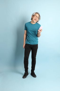 Mavi arka plandaki kıdemli Asyalı adam..