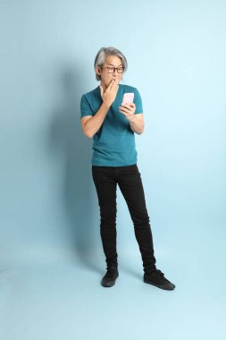 Mavi arka plandaki kıdemli Asyalı adam..