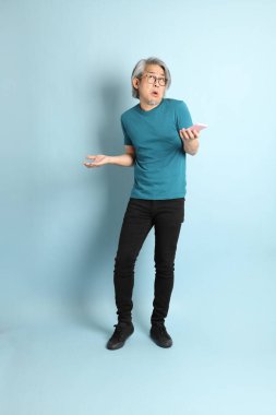 Mavi arka plandaki kıdemli Asyalı adam..