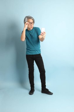 Mavi arka plandaki kıdemli Asyalı adam..