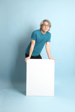 Mavi arka plandaki kıdemli Asyalı adam..