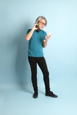 Mavi arka plandaki kıdemli Asyalı adam..