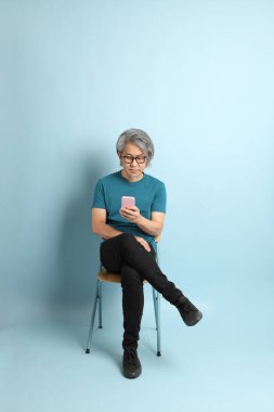 Mavi arka plandaki kıdemli Asyalı adam..