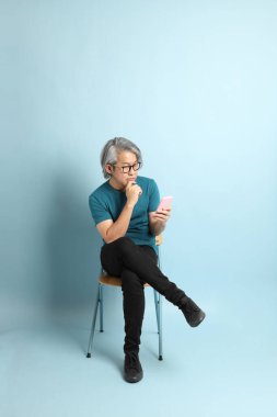 Mavi arka plandaki kıdemli Asyalı adam..