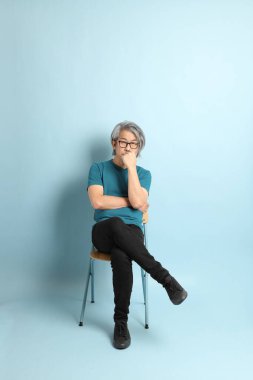 Mavi arka plandaki kıdemli Asyalı adam..