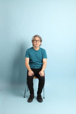 Mavi arka plandaki kıdemli Asyalı adam..