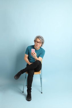 Mavi arka plandaki kıdemli Asyalı adam..