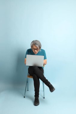 Mavi arka plandaki kıdemli Asyalı adam..