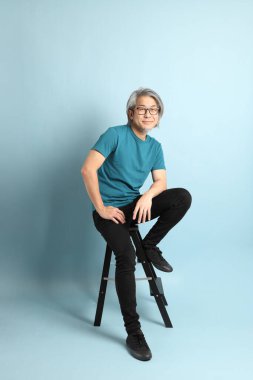 Mavi arka plandaki kıdemli Asyalı adam..