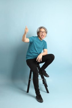 Mavi arka plandaki kıdemli Asyalı adam..