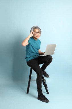 Mavi arka plandaki kıdemli Asyalı adam..