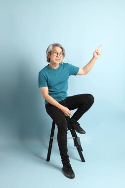 Mavi arka plandaki kıdemli Asyalı adam..