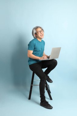 Mavi arka plandaki kıdemli Asyalı adam..