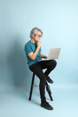 Mavi arka plandaki kıdemli Asyalı adam..