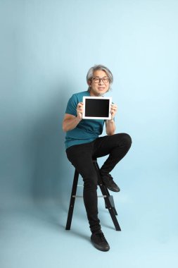 Mavi arka plandaki kıdemli Asyalı adam..