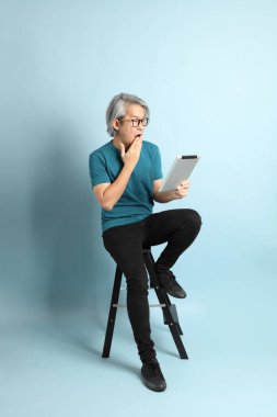 Mavi arka plandaki kıdemli Asyalı adam..