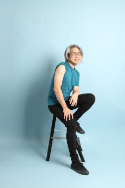 Mavi arka plandaki kıdemli Asyalı adam..