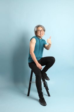 Mavi arka plandaki kıdemli Asyalı adam..