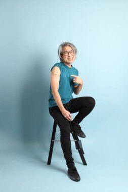 Mavi arka plandaki kıdemli Asyalı adam..