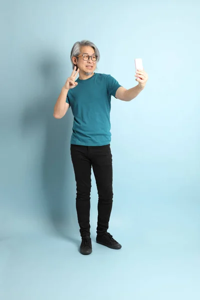 Mavi arka plandaki kıdemli Asyalı adam..