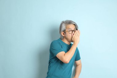 Mavi arka plandaki kıdemli Asyalı adam..