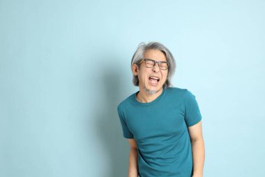 Mavi arka plandaki kıdemli Asyalı adam..