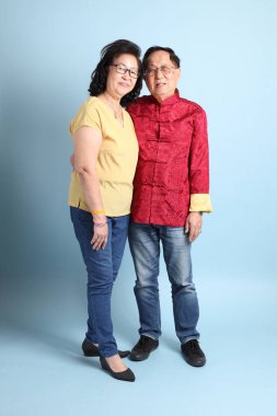 Mavi arka planda duran kıdemli Asyalı çift..