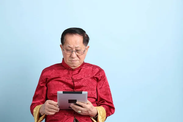 Senior Asian Man Wearing Traditional Chinese Shirt Sitting Blue Background - Stock-foto