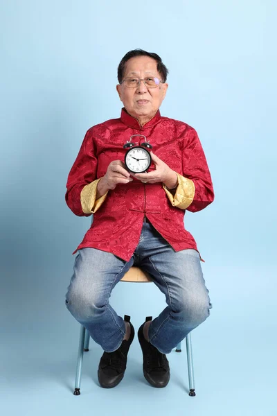 Senior Asian Man Wearing Traditional Chinese Shirt Sitting Blue Background - Stock-foto