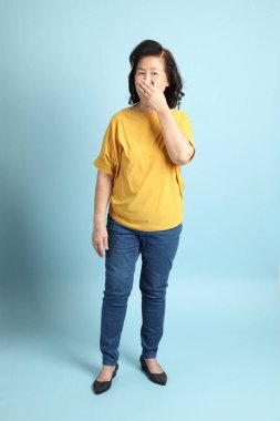 Mavi arka plandaki kıdemli Asyalı kadın..