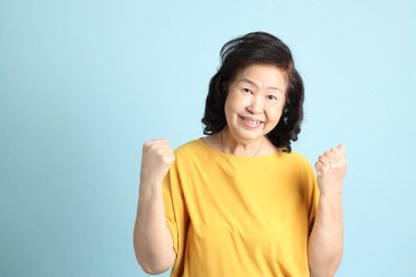 Mavi arka plandaki kıdemli Asyalı kadın..